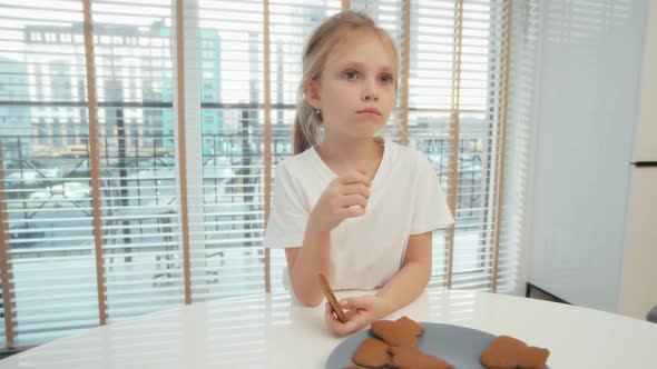 Little girl eat ginger cookies on the kitchen at home