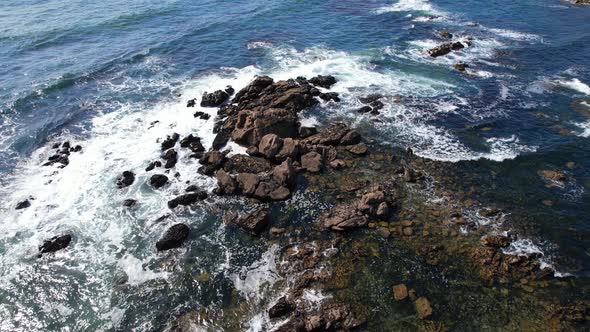 Beautiful Aerial View Waves Break on Rocks in a Blue Ocean