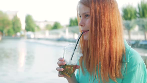 Beautiful young woman with lemonade and red hair alt