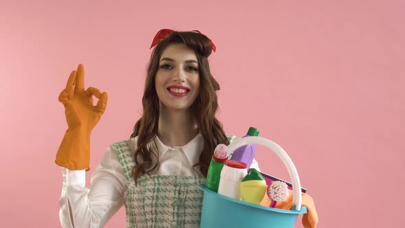 The Woman Holds a Bucket of Cleaning Tools in Her Hand and Makes a Gesture of Ok