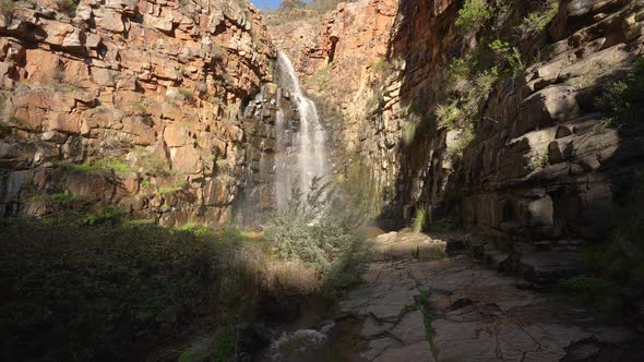 Waterfall coming down with some beautiful sunlight and a rainbow in the middle alt