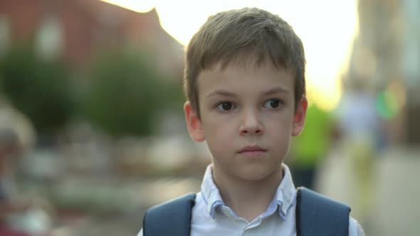 Closeup Portrait of a Boy with a Backpack Outdoors Looking at the Camera