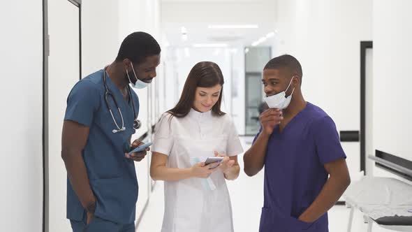 Female Doctor in a White Robe Shows Something on His Smartphone to His Graduate Students During a
