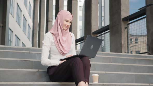 Portrait of Attractive Arabian Woman in Elegant Clothes and Hijab Sitting on alt