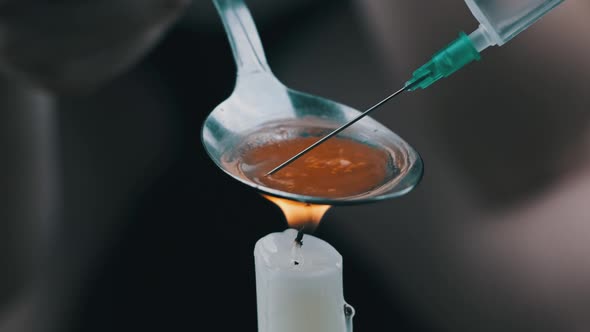 Preparing a Dose of Heroin in a Spoon Over a Candle Flame alt