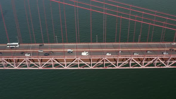 Side Slider View of Busy Multi Lane Traffic Across a Red Bridge Over the Sea alt