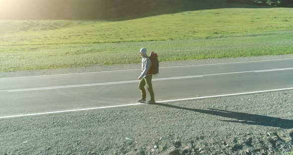 Flight Over Hitchhiker Tourist Walking on Asphalt Road alt