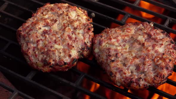 Two Meat Burger Cutlet with Onions Are Roasting on the Grill Above the Open Fire alt