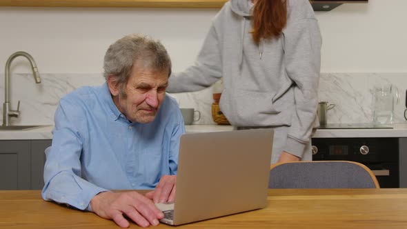 Happy Grandfather and Daughter Hugging Looking at Something on a Laptop at Home alt