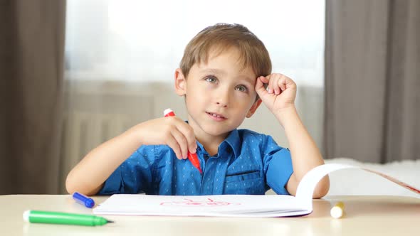 A Little Caucasian Boy Spends Time Drawing with Colored Pencils While Sitting at a Table, The Child alt