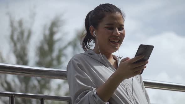 Smiling portrait beautiful young Asian woman fitness runner standing using mobile phone.