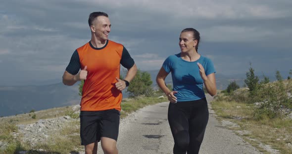Tracking Slow Motion Shot of Sportive Couple Jogging Outdoors in the Morning Trail Running alt