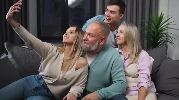 Cheerful Family Sitting on the Sofa in the Living Room a Girl Takes a Selfie with Relatives Children alt