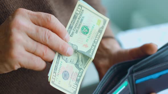 Close Up View of an Old Man's Hands Adding Dollar Bills to His Wallet alt