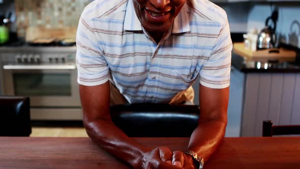 Portrait of senior man smiling at camera in kitchen alt