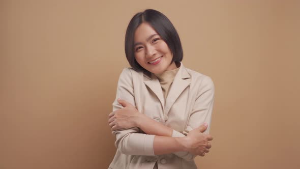 Asian business woman smiling and hug her self feeling of pride and happiness isolated