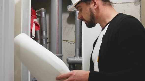 Master Builder in Hard Hat with Design Drawings at Construction Site. Worker with Construction alt