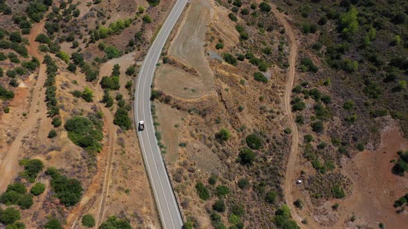 Car Drives on Winding Road Among Scrublands in Highland alt