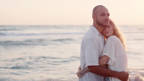 Young Beautiful Couple in Love Standing and Hugging on Beach By the Sea