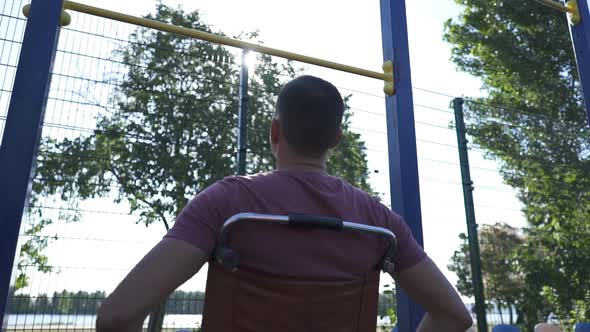 Young Disabled Man in Wheelchair Engaged on the Crossbar Outdoors