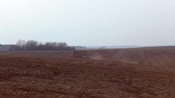 Modern tractor plows a field, moving for the camera.