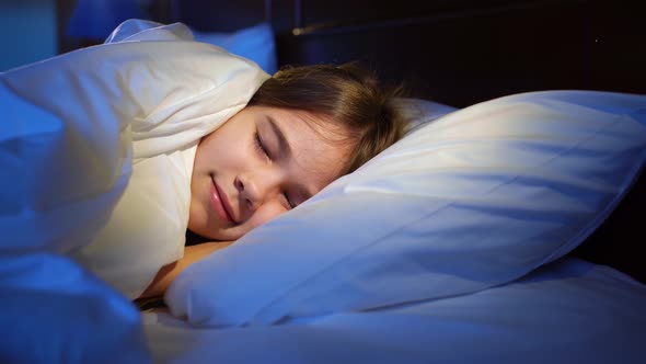The Girl Naps in Bed Sees a Pleasant Sleep Smiles Opens Eyes and Wakes Up alt