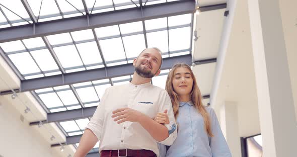 Beautiful Young Couple Walking and Talking on a Shopping Center Holding Hands alt