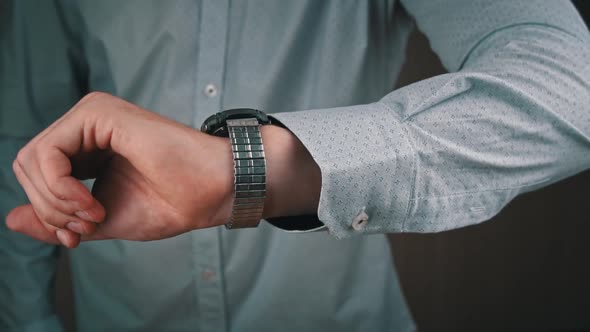 Man Businessman in a Shirt Looks at His Wrist Watch alt