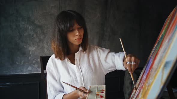 Young Woman Painter is Drawing a Portrait on Canvas in Modern Art Style While Working at Home alt