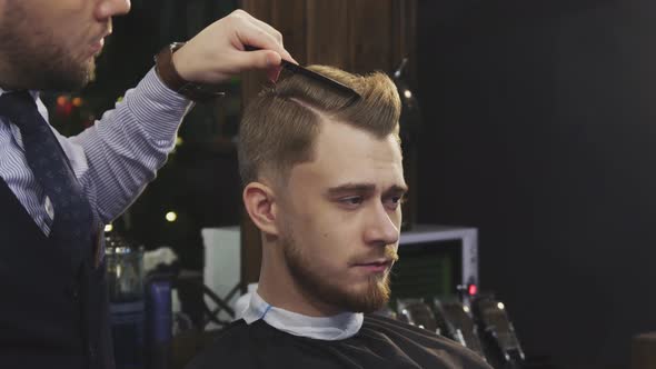 Professional Barber Using Hairspray and Blow Dryer Styling Hair of a Client alt