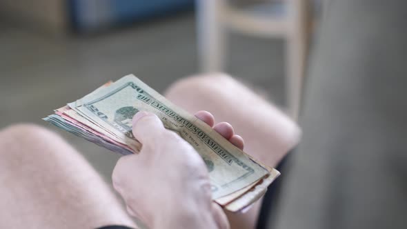 Men's Hands Count Cash Dollars and Other Currencies at Home in a Bright Room alt