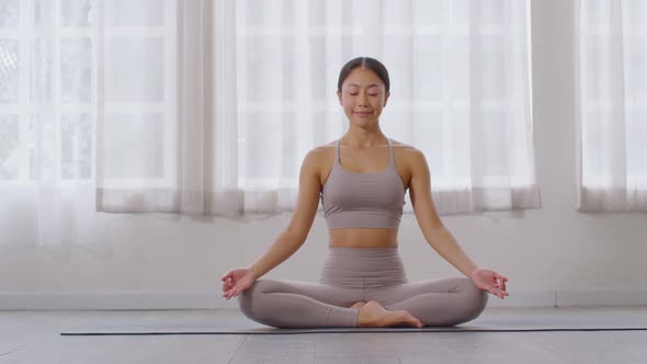 Calm of Attractive Asian woman and grey sport ware practice yoga lotus pose to meditation at home alt