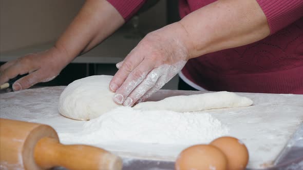 Closeup Hands of Senior Female is Cuts a Dough Into Pieces at Home Kitchen alt
