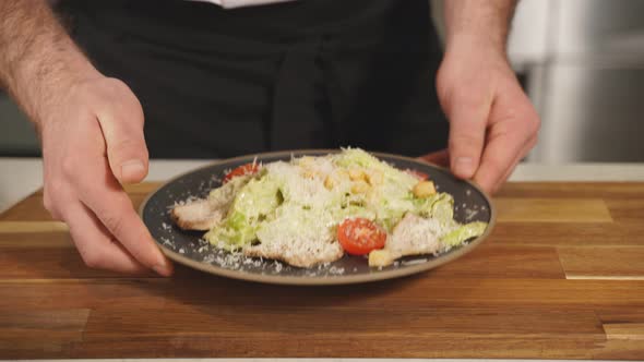 The Chef Serves a Delicious Caesar Salad Cooked on a Black Plate