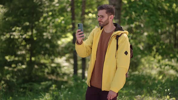 Man Hiker Using Smartphone While Enjoying Weekend in Forest alt