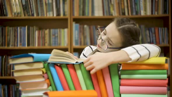 Girl in Glasses Leafing Through a Book in the Library