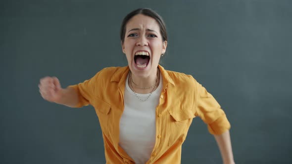 Portrait of Young Lady Screaming and Gesturing Looking at Camera Fighting Expressing Rage alt