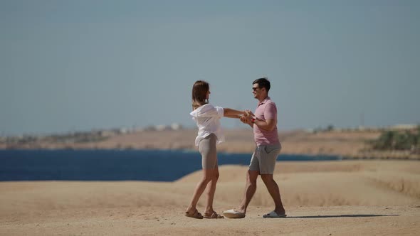 a Woman with Long Hair in a White Shirt and a Man in a Pink Tshirt Embrace and Hold Hands on a alt