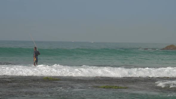Fisherman Walks Along Water Surf Edge at Foaming Ocean Waves alt