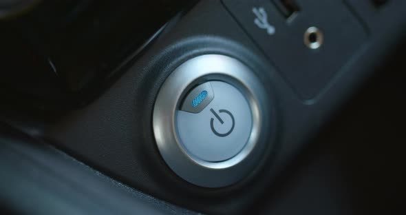 Female Finger Pressing an Engine Start Stop Button on Modern Electric Car alt