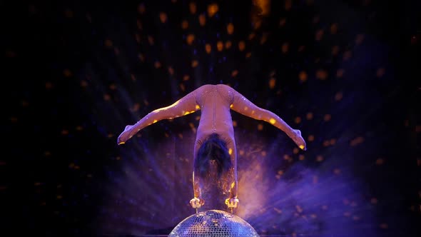 The Gymnast Performs an Acrobatic Number on a Mirror Ball, Stock Footage