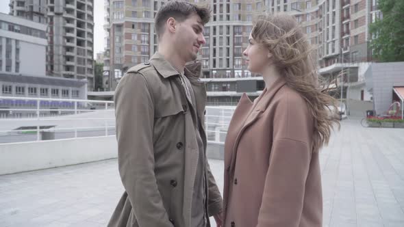Camera Approaches To Young Man Kissing Woman on Windy Urban Street. Side View Portrait of Young alt
