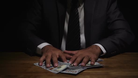 Businessman giving bribe money on the table in dark room