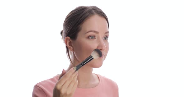 Portrait of Young European Woman Making Blush or Powder on the Face Using Makeup Brush