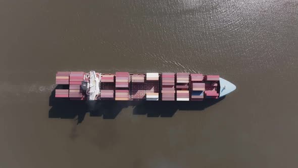 Cargo ship on a river followed by 2 tug boats alt