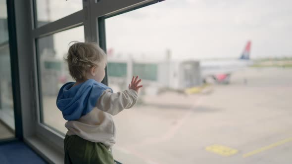 Little Boy Watching Planes at the Airport Standing in Silhouette with His Back to the Camera at a alt