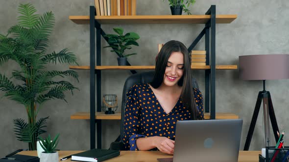 Businesswoman in home office puts on wireless earphones connects to online video call webcam laptop alt