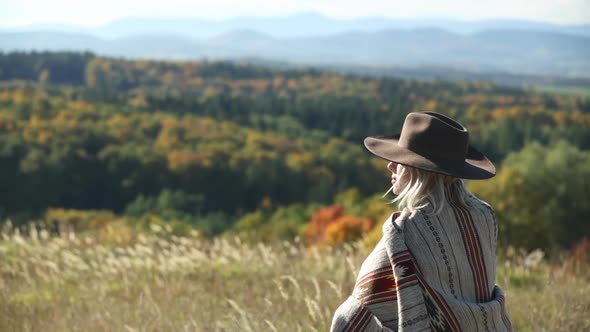 Woman in poncho at outdoor with Sudety mountains in autumn season on background