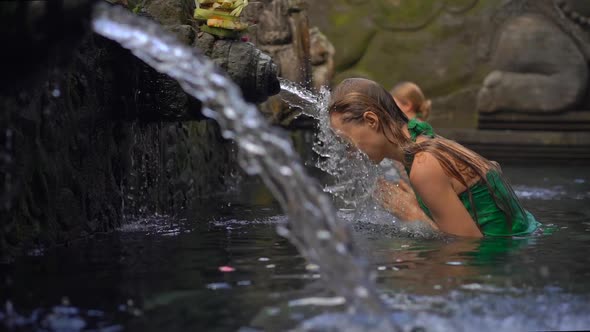 Slowmotion Shot of a Young Woman Visiting the Holly Springs in Indonesia. Tirta Empul Holy Water alt