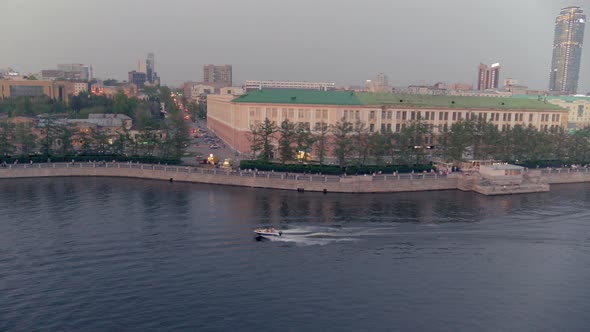 An Aerial View of a Boat That Floats on a River in the City Centre at Sunset alt
